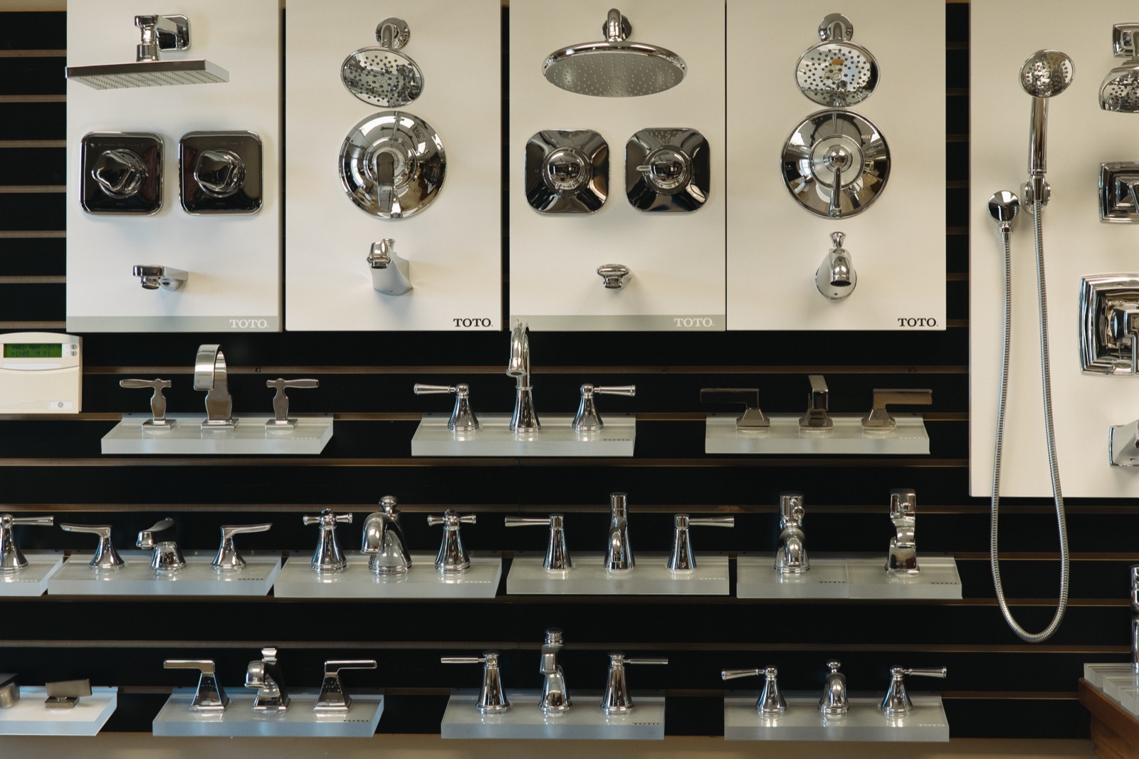 A.J. Alberts Plumbing showroom interior wall in Woodbury, Minnesota, featuring working displays of TOTO and Kohler faucets, fixtures, and shower systems