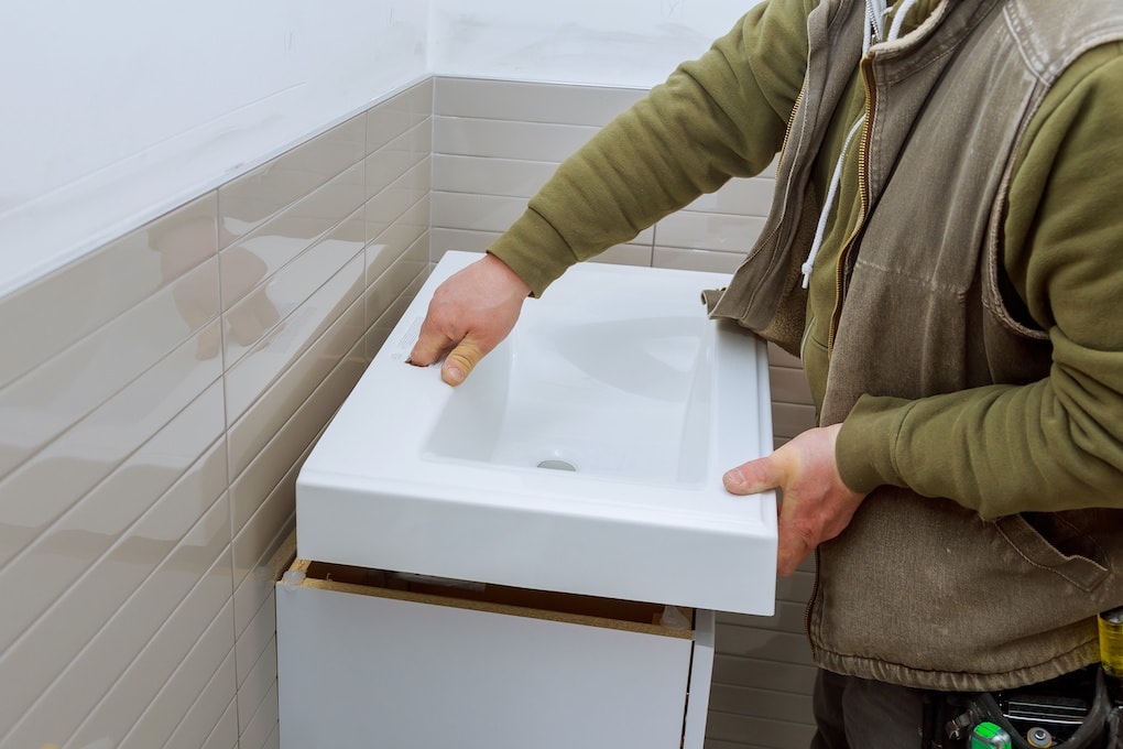 man removing a bathroom vanity top