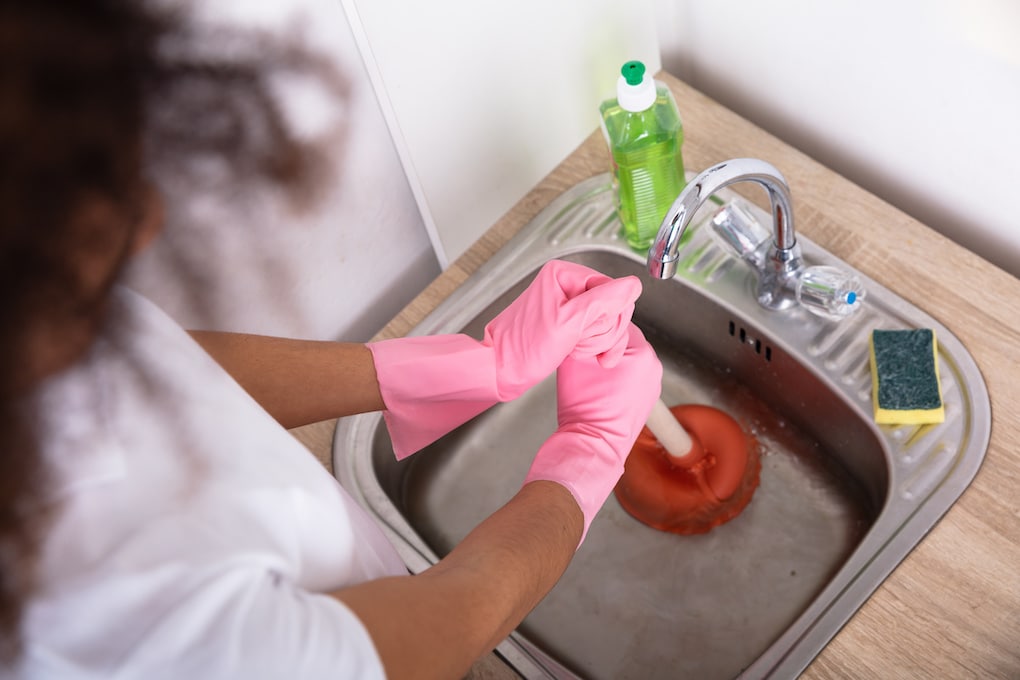 female using plunger after learning how to unclog a sink