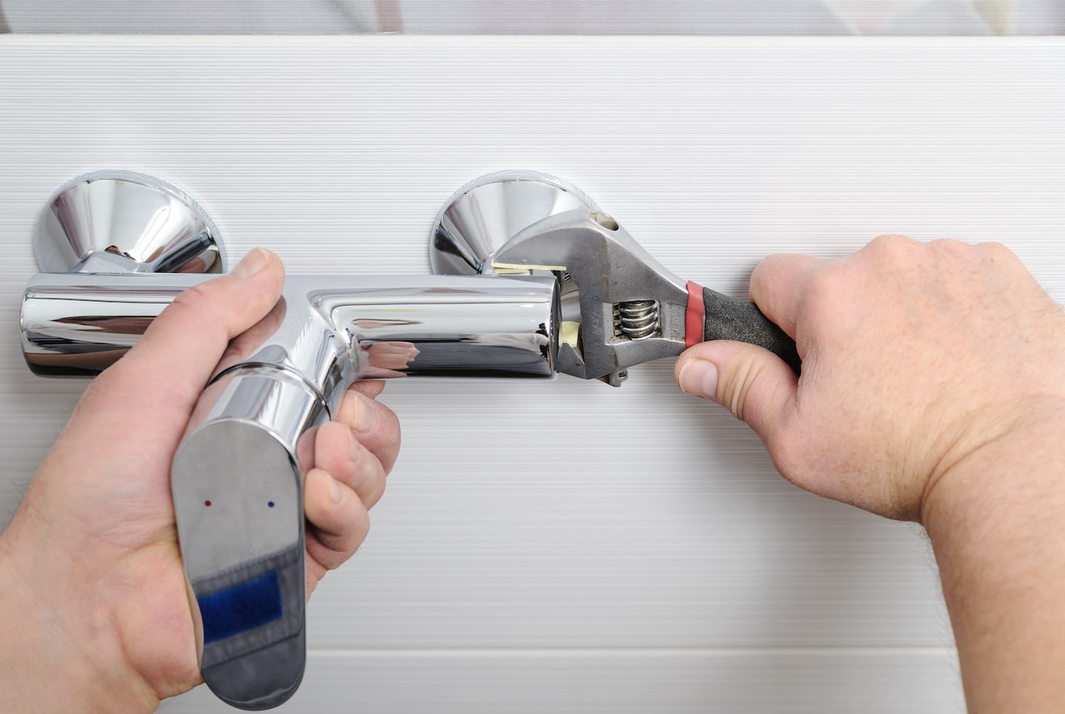 how to increase water pressure in shower view of two hands tightening handles on a bathroom shower fixture