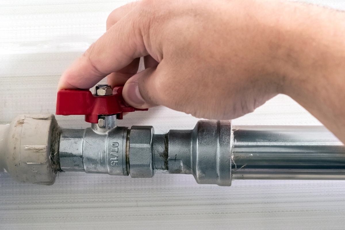 plumber turns off water supply using valve before fixing toilet