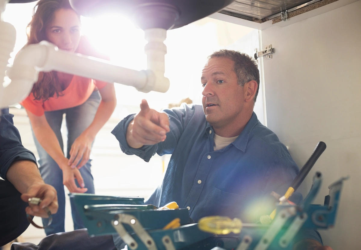 plumber pointing at sink piping in the kitchen