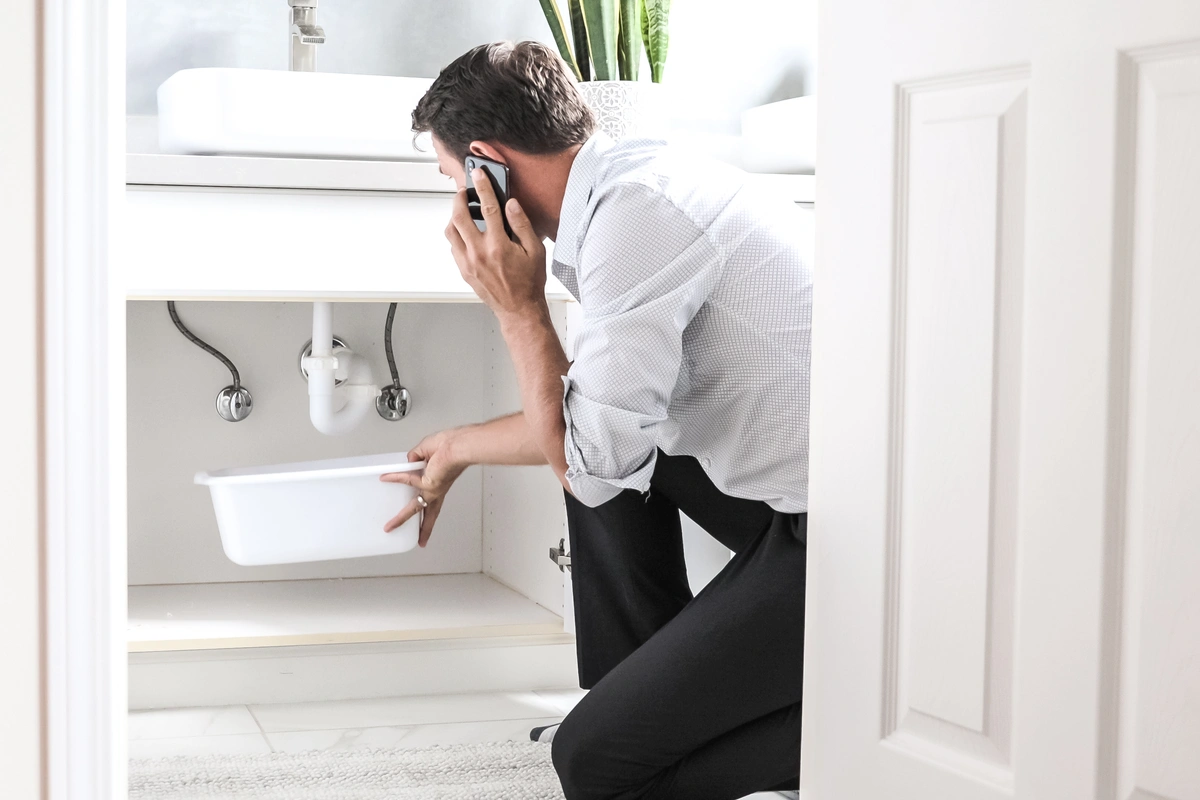 man holding bucket for leaking faucet