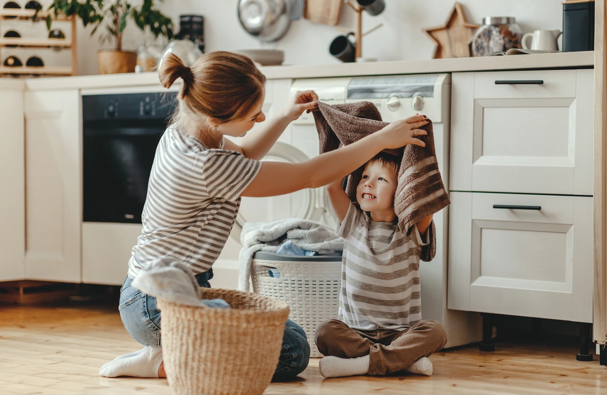 Mother and son fold and play with laundry