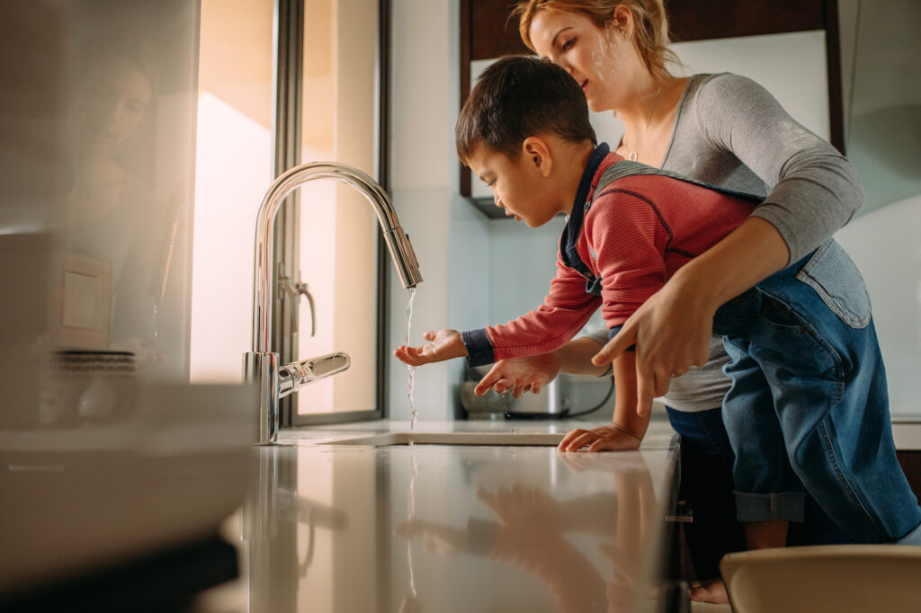 mother and son washing hands in kitchen repair and installation sink