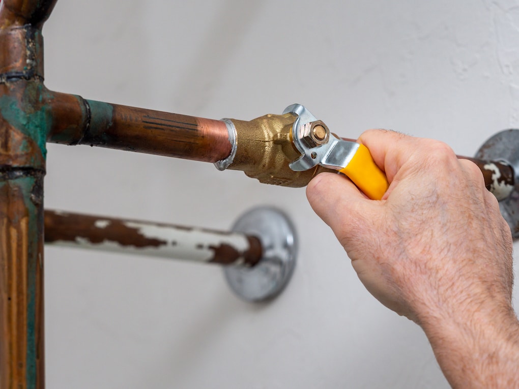 Plumber turning water shut off valve to combat low water pressure