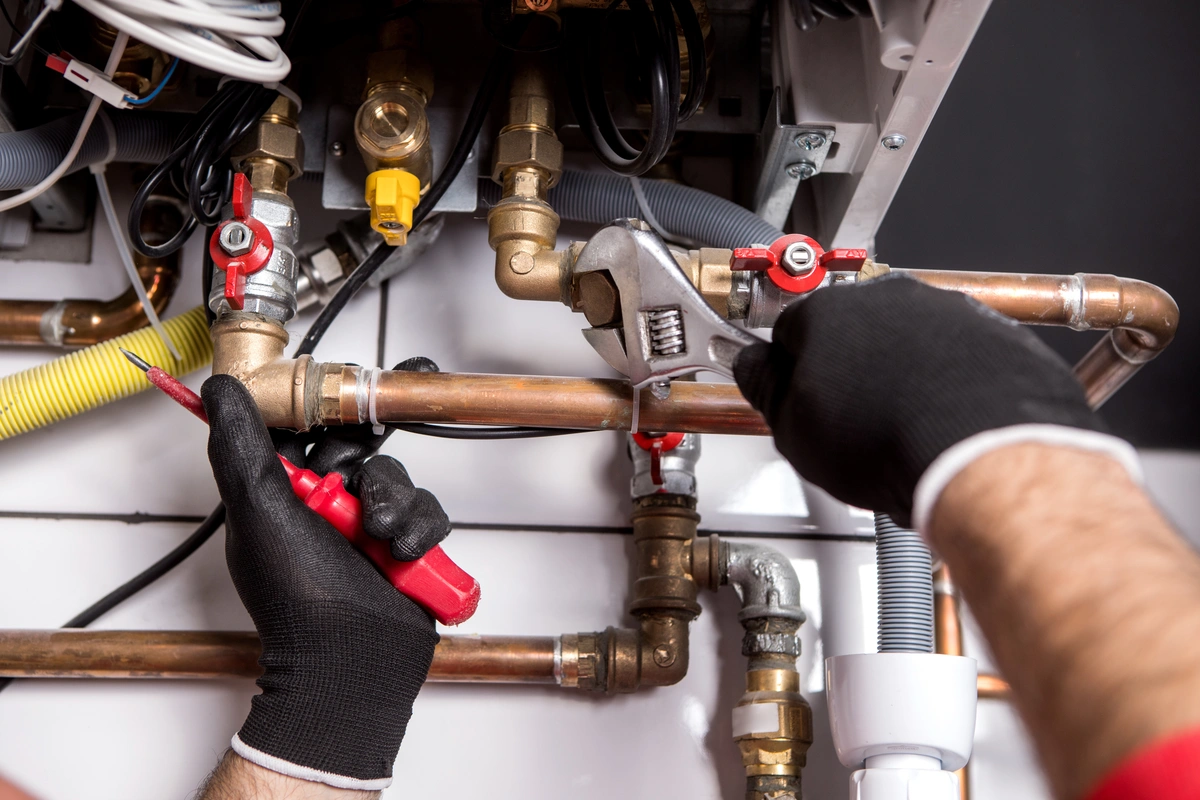 plumber wearing gloves fixing the house heating system with copper pipes