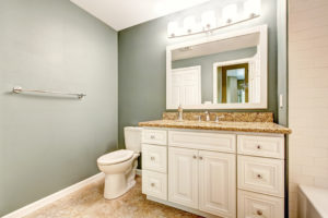 White bathroom vanity cabinet with granite top and mirror.