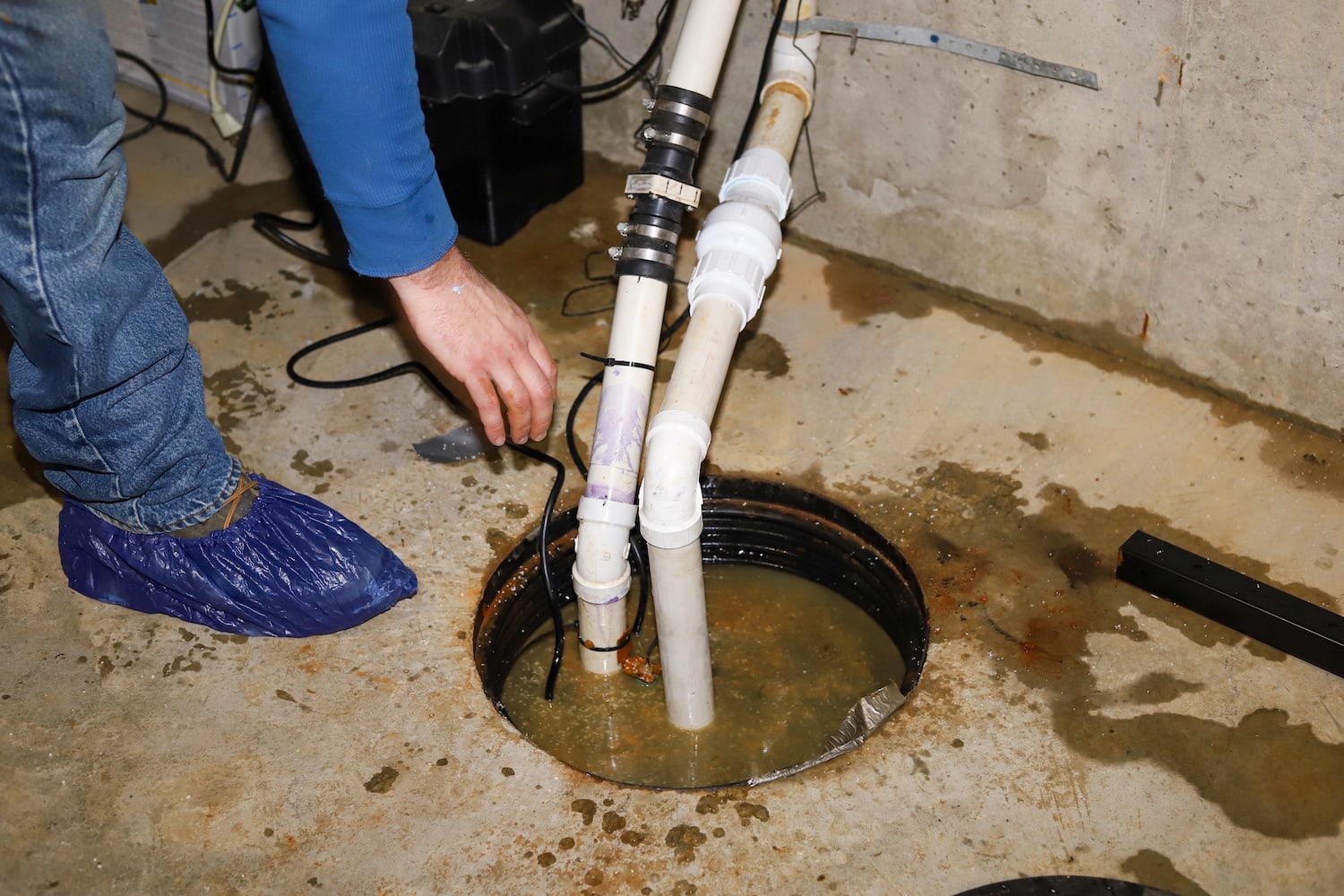 sump pump maintenance view of repairman fixing broken backup sump pump in basement