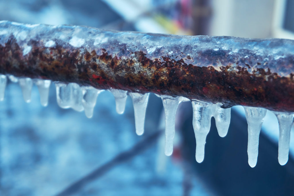 a frozen copper pipe with icicles